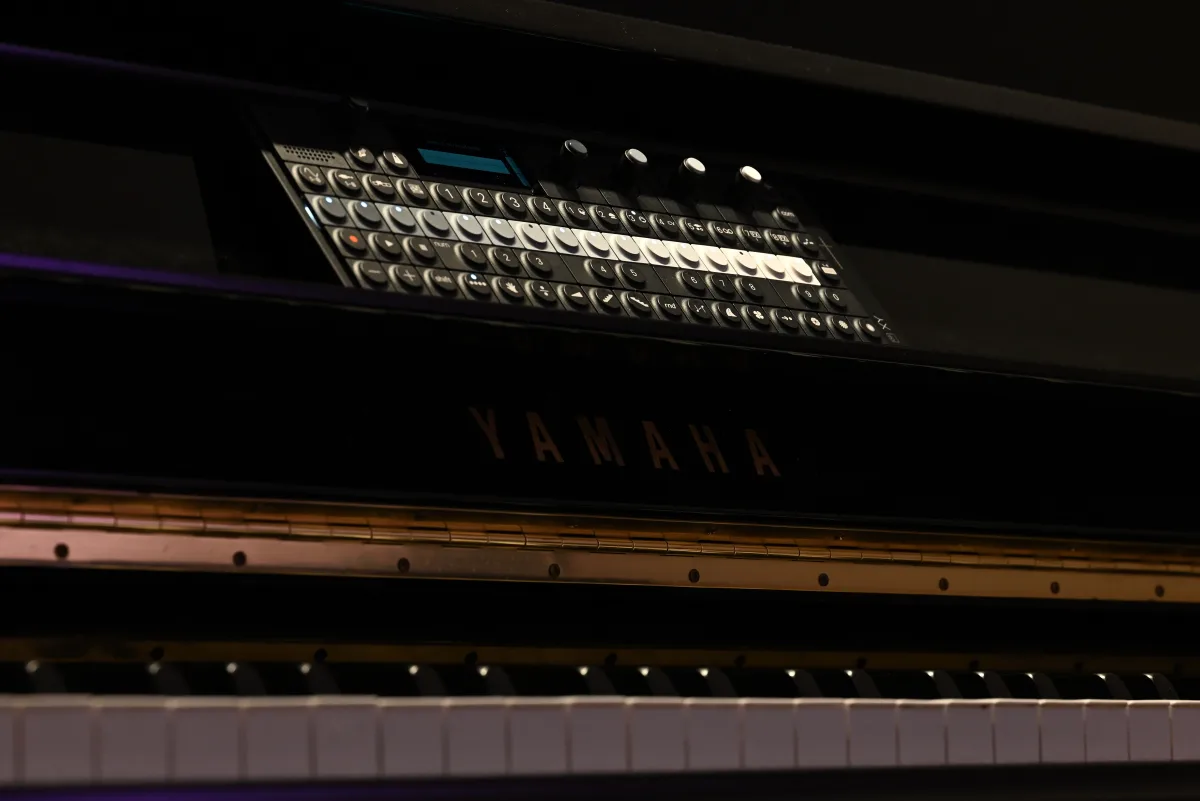 The OP-XY sitting on an upright piano's music stand.