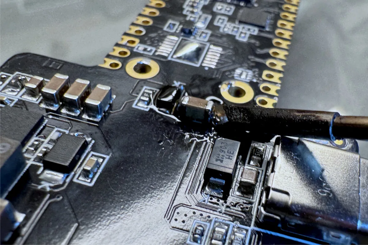 A photo of the TS21-KU tip being used to desolder one of the terminals from an SMT ceramic capacitor.