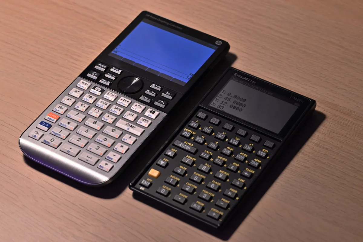 A photo of the DM42n and an HP Prime next to each other, showcasing the size difference between the two, with the DM42n being the much smaller unit.