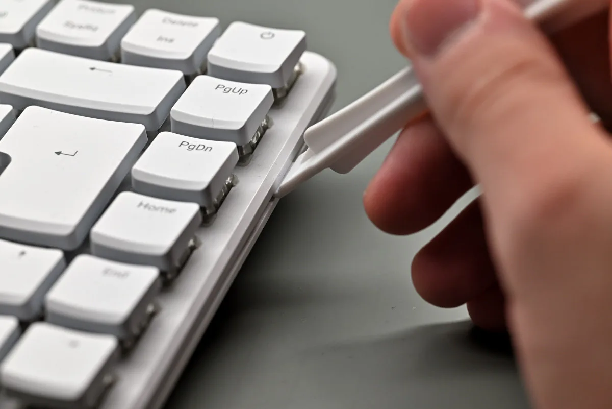 A photo showing the included spudger being used to unclip the board's latches.