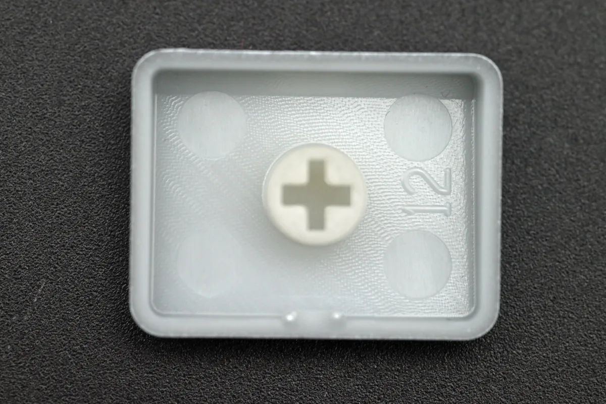 A close-up shot of the underside of the keycap, revealing its single-shot structure with a sprayed-on white coating.