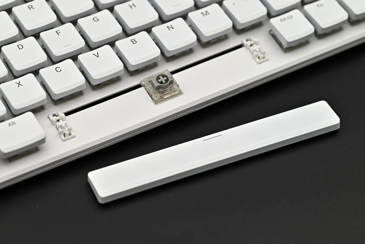 A photo showing the spacebar keycap removed, with two stabilizer posts visible on either side of the switch.