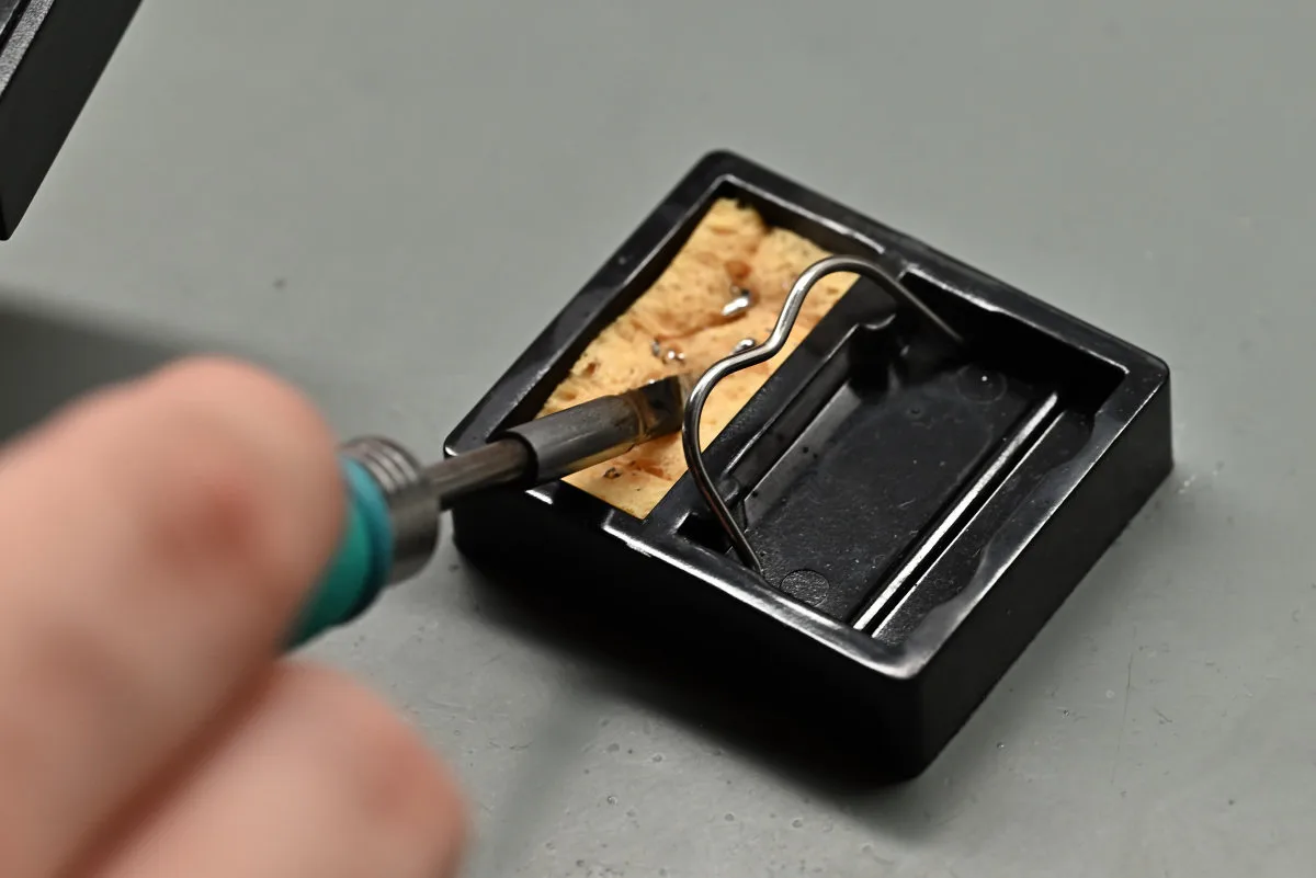 A photo showing the TS1M's C245 cartridge tip being cleaned using a soldering stand's sponge.