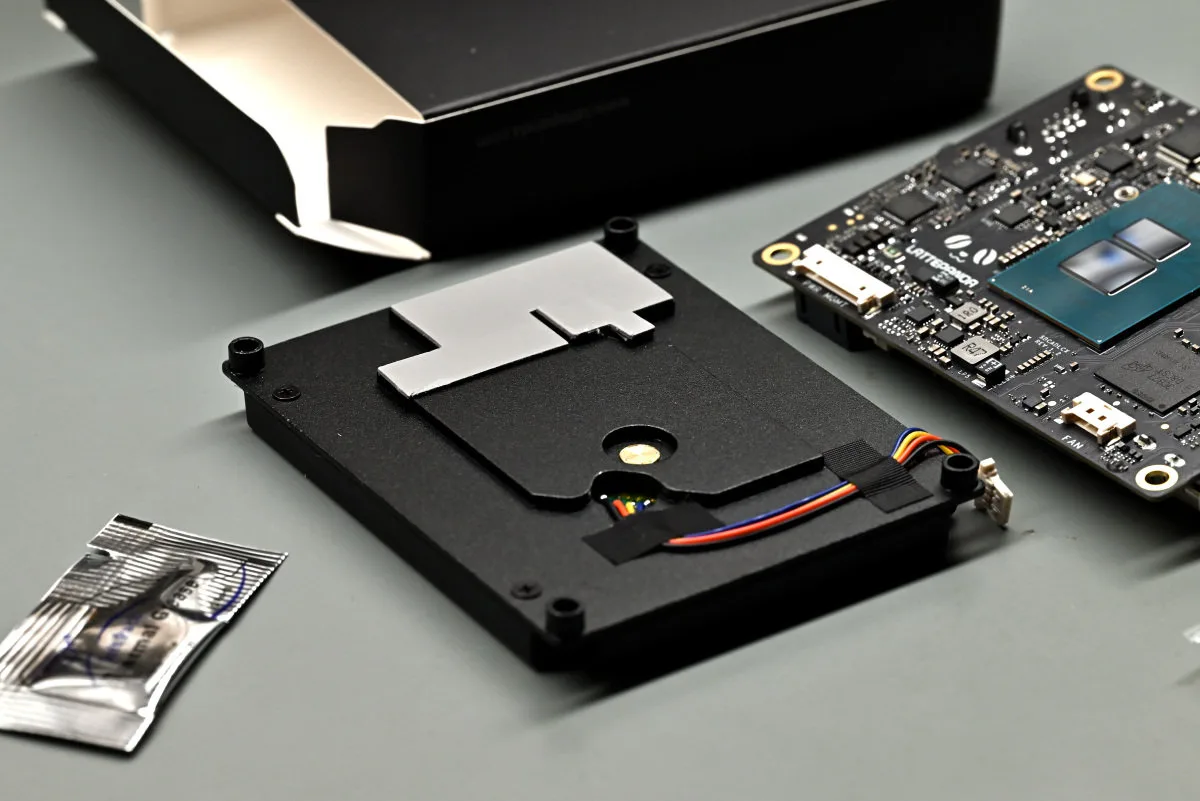 A photo of the official cooler on its back, with the thermal pads applied, and thermal paste ready to be applied to the CPU block.