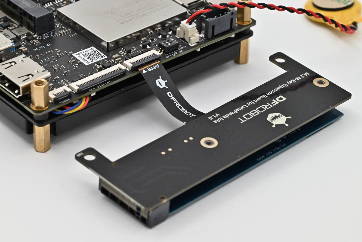 A photo of the M.2 expansion board being attached to the LattePanda Iota. The ribbon cable that connects the two is clearly marked "board", to show the right orientation.