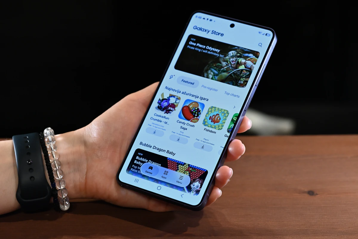 A photo of a hand holding the S26 Ultra, with the Galaxy Store app storefront open.